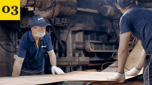 Workers cutting maple veneers on industrial machinery