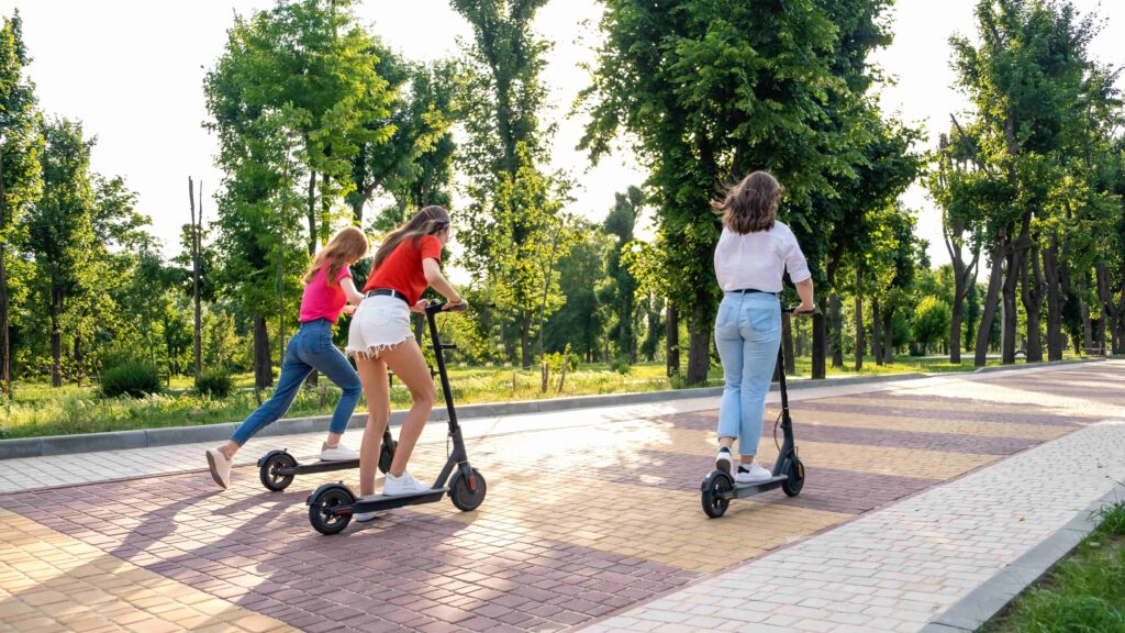 Two people riding scooters in a park