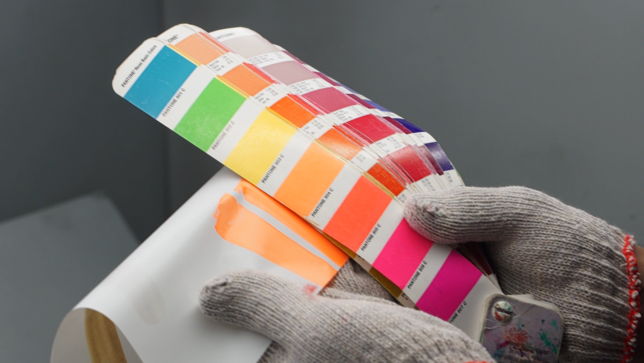 Worker comparing printed skateboard graphic colors against a color chart