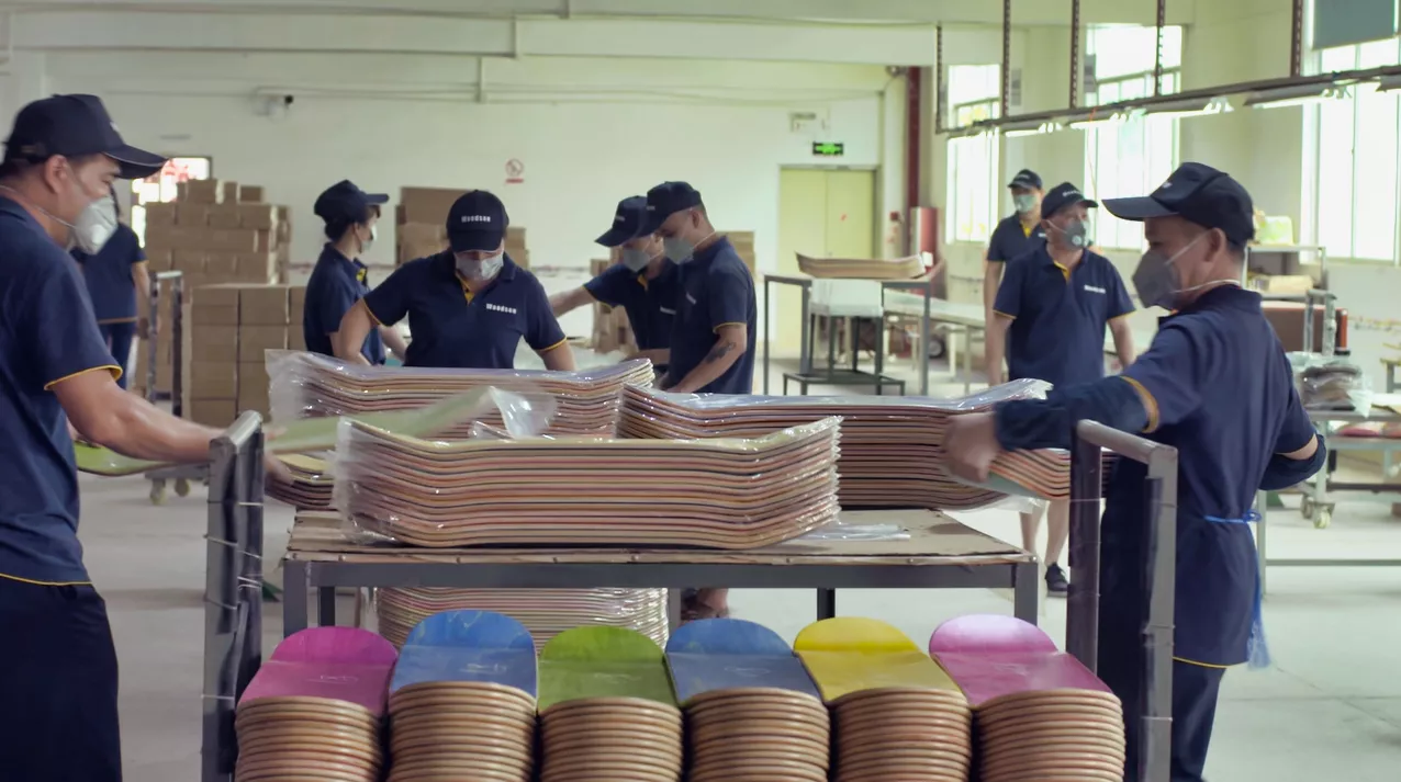 Factory workers arranging maple veneers for skateboard deck production