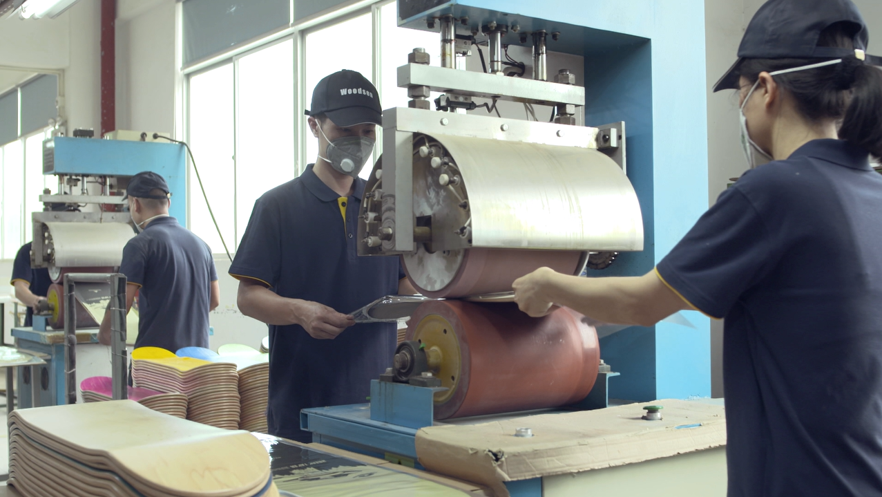 Workers operating skateboard graphic printing equipment