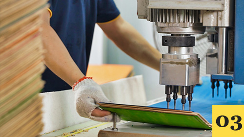 Machine drilling truck mounting holes in a skateboard deck