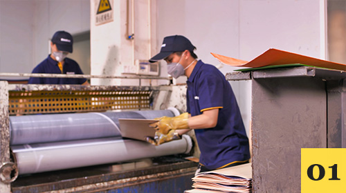Worker passing maple veneers through a glue coating machine