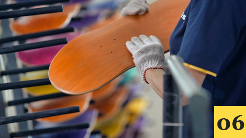Worker inspecting the finish of a skateboard deck