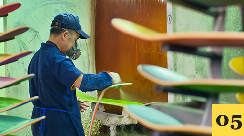 Worker spraying varnish onto skateboard decks